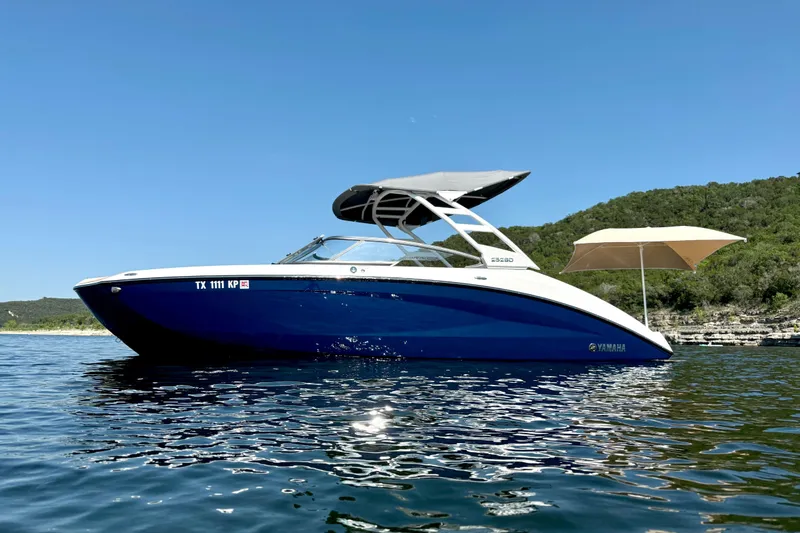 The Image of 2022 Yamaha Boats 252SD on water, blue hull, canopy, scenic background. - 0