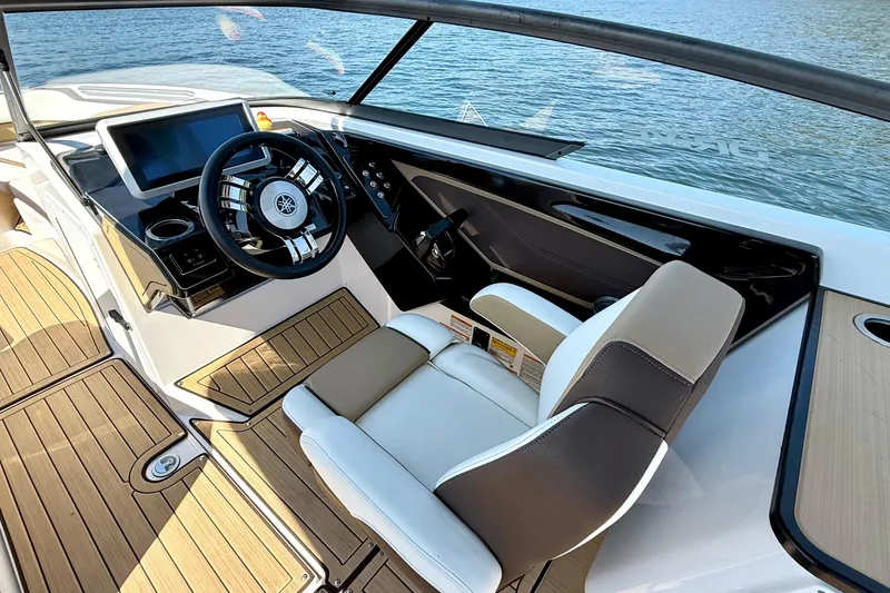 Slide: The Image of 2022 Yamaha Boats 252SD cockpit with modern steering and dashboard, overlooking water. - 16
