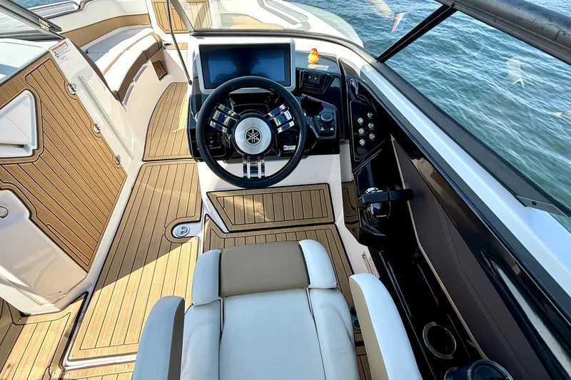 Slide: The Image of 2022 Yamaha Boats 252SD cockpit with modern steering and wood accents on water. - 17