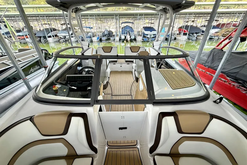 Slide: The Image of 2022 Yamaha Boats 252SD interior with sleek seating and modern design in a marina setting. - 23