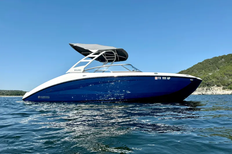 Slide: The Image of 2022 Yamaha Boats 252SD on water, blue hull, sunny day, scenic background. - 4