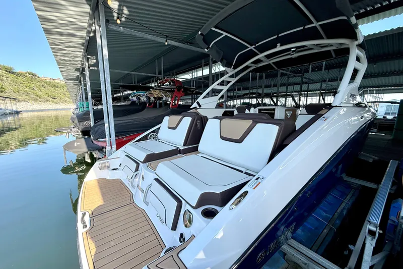 Slide: The Image of 2022 Yamaha Boats 252SD docked, showcasing sleek design and spacious seating under a covered marina. - 9