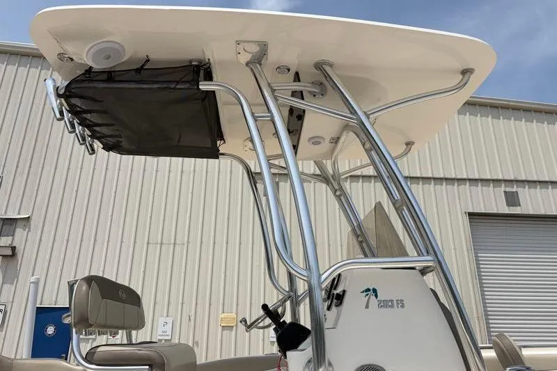Slide: The Image of 2024 Key West 203 FS boat with T-top and seating, docked near a warehouse. - 19