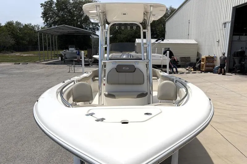 Slide: The Image of 2024 Key West 203 FS boat, white exterior, parked outdoors near a warehouse. - 7