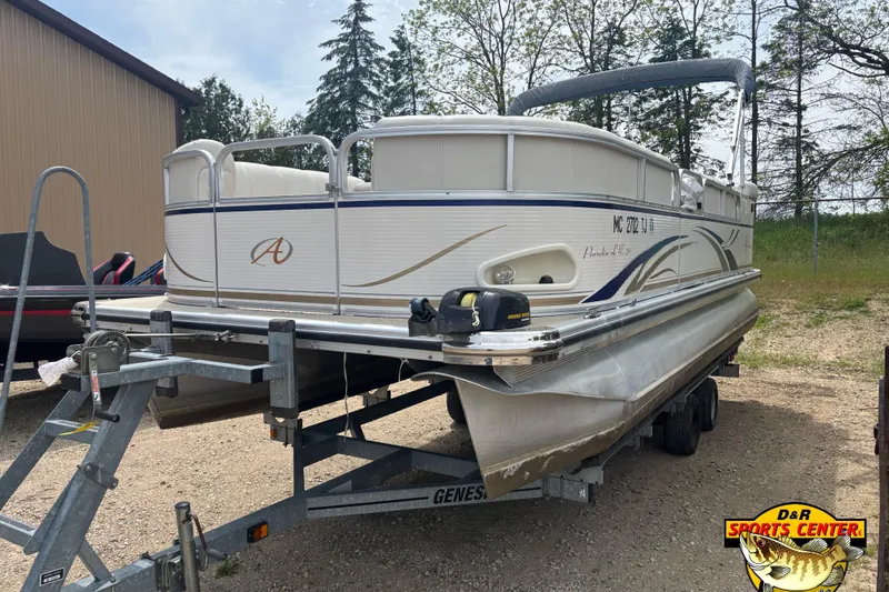 Slide: The Image of 2008 Avalon Paradise 20' pontoon boat on trailer, parked outdoors near a building. - 2