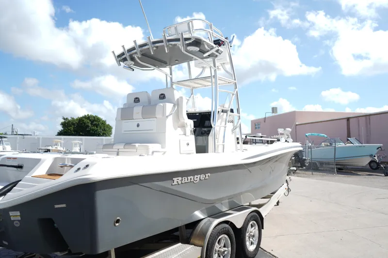Slide: The Image of 2021 Ranger 2600 Bay boat on trailer under a clear blue sky. - 2