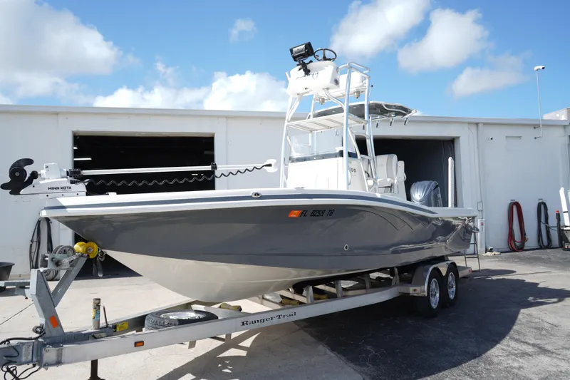 Slide: The Image of 2021 Ranger 2600 Bay boat on trailer, parked outside a garage under a blue sky. - 4