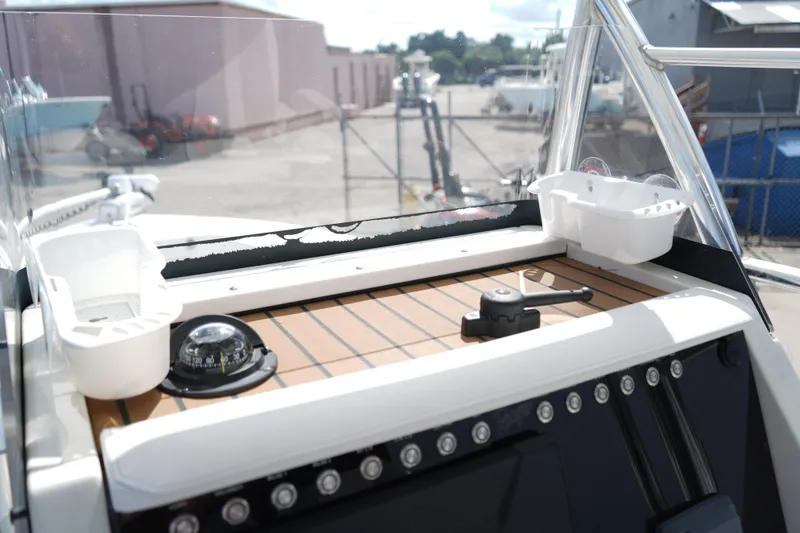 Slide: The Image of 2021 Ranger 2600 Bay boat dashboard with compass and controls in a marina setting. - 8