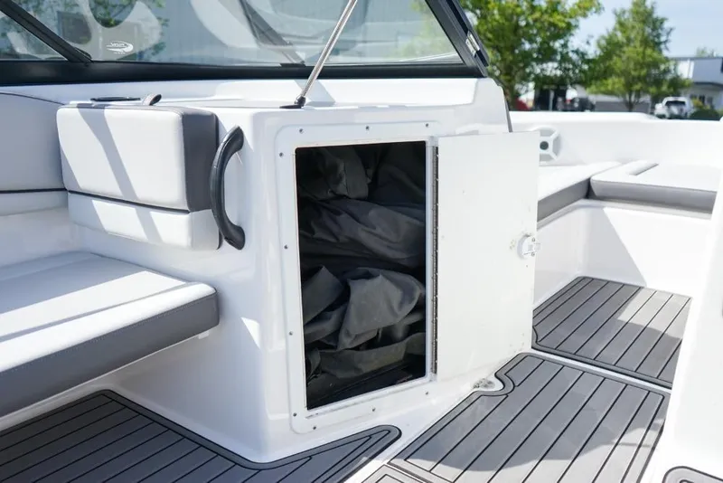 Slide: The Image of 2019 Yamaha Boats AR190 interior storage compartment with open door, showcasing seating and flooring. - 15