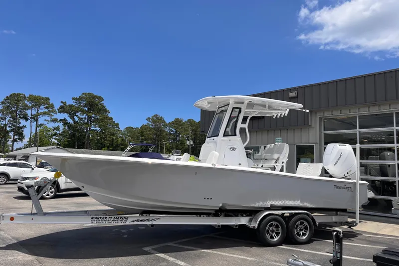 The Image of 2026 Tidewater 2500 Carolina Bay boat on trailer, parked outside dealership under clear blue sky. - 0