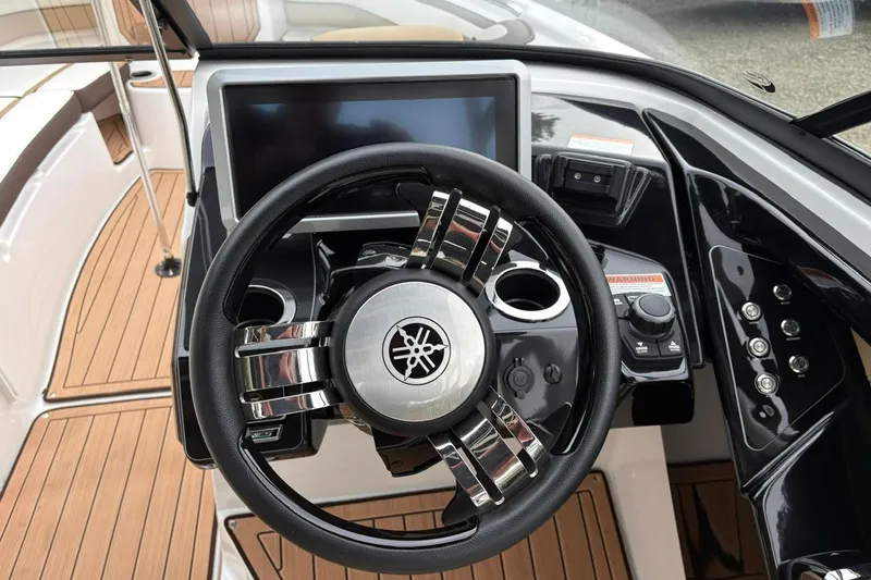 Slide: The Image of 2023 Yamaha Boats 252SD steering wheel and dashboard with modern controls and wood accents. - 14