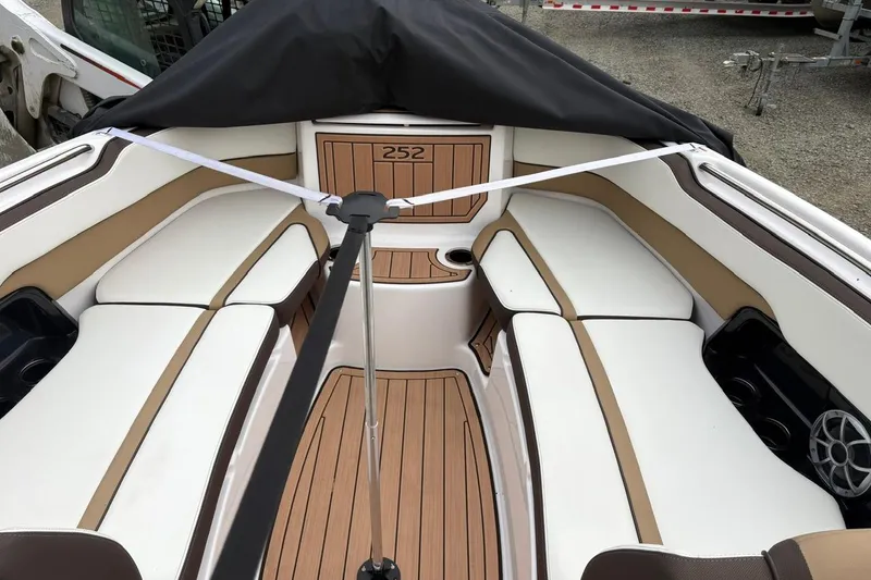 Slide: The Image of 2023 Yamaha Boats 252SD interior with white and tan seating, wood accents, and cup holders. - 15