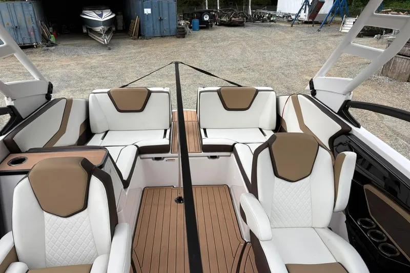 Slide: The Image of 2023 Yamaha Boats 252SD interior with white and brown seating, docked outdoors. - 16