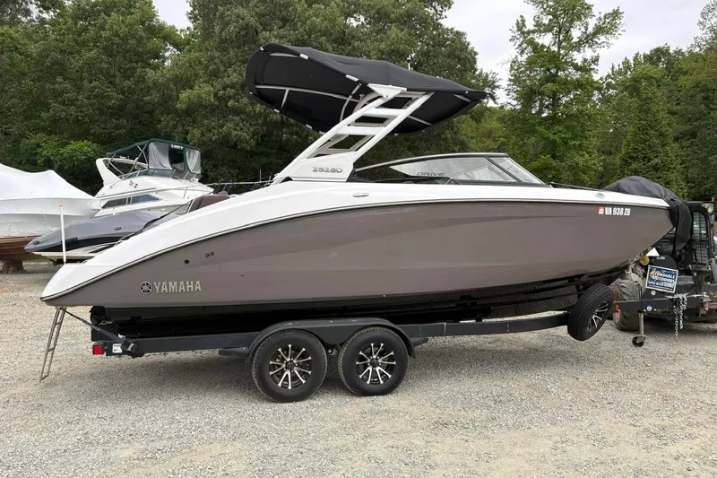Slide: The Image of 2023 Yamaha Boats 252SD on trailer, parked outdoors with trees in background. - 3