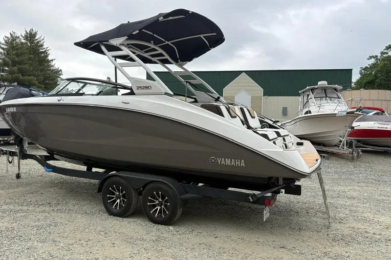 Slide: The Image of 2023 Yamaha Boats 252SD on trailer, parked outdoors with other boats. - 4