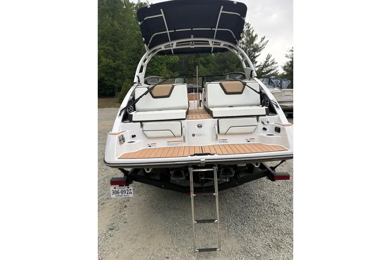Slide: The Image of 2023 Yamaha Boats 252SD with swim platform and ladder, parked on gravel. - 6