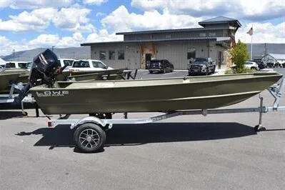 The Image of 2024 Lowe L1648M Aura Jon boat on trailer, parked outdoors under a cloudy sky. - 0