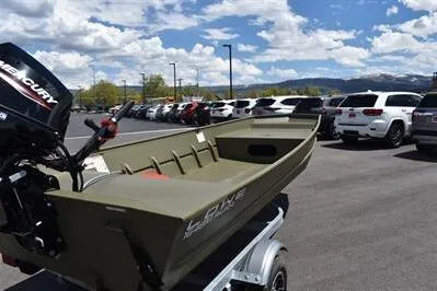 Slide: The Image of 2024 Lowe L1648M Aura Jon boat on trailer, parked in lot under blue sky. - 4