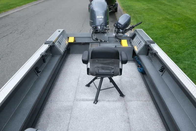 Slide: The Image of 2021 Alumaweld Super Vee 20 boat interior with seating and motor, parked on pavement. - 10
