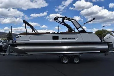 The Image of 2026 Princecraft Vogue 25 RL pontoon boat on trailer under a partly cloudy sky. - 0