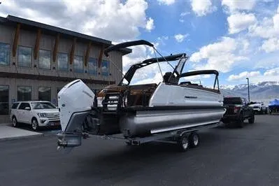 Slide: The Image of 2026 Princecraft Vogue 25 RL pontoon boat on trailer, parked outside a modern building. - 3