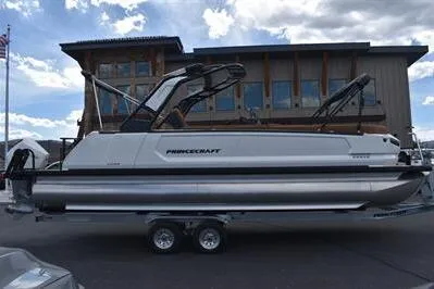 Slide: The Image of 2026 Princecraft Vogue 25 RL pontoon boat on trailer, parked outdoors. - 4