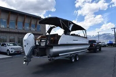 Slide: The Image of 2026 Princecraft Vogue 25 RL pontoon boat on trailer, parked outdoors under a blue sky. - 47