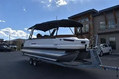 Slide: The Image of 2026 Princecraft Vogue 25 RL pontoon boat on trailer, parked outdoors under a clear sky. - 49