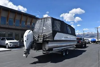 Slide: The Image of 2026 Princecraft Vogue 25 RL pontoon boat on trailer, covered, parked outdoors. - 56