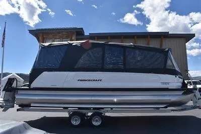Slide: The Image of 2026 Princecraft Vogue 25 RL pontoon boat with canopy, parked on a trailer under a blue sky. - 57
