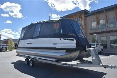Slide: The Image of 2026 Princecraft Vogue 25 RL pontoon boat on trailer, covered, parked outdoors. - 58