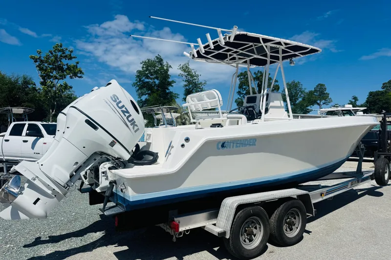 Slide: The Image of 1996 Contender 23 CC boat on trailer with Suzuki outboard motor, under clear blue sky. - 2
