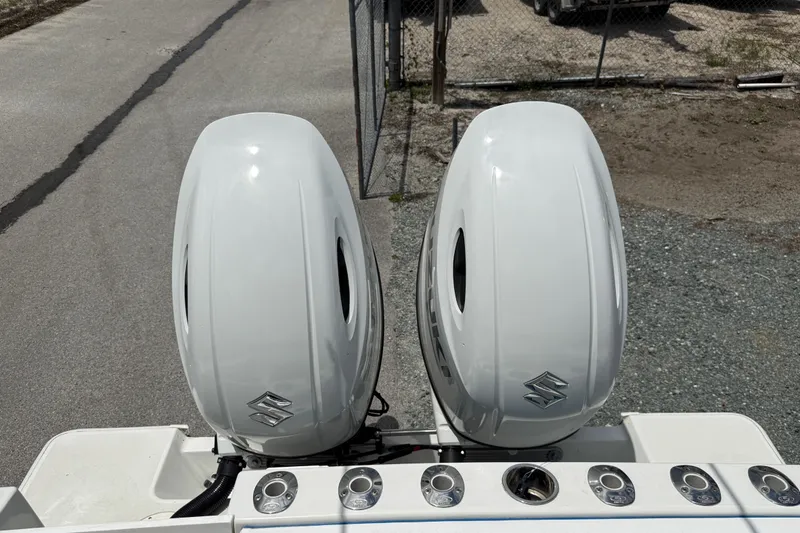 Slide: The Image of Twin Suzuki outboard motors on a 1996 Contender 23 CC boat, parked on gravel. - 7