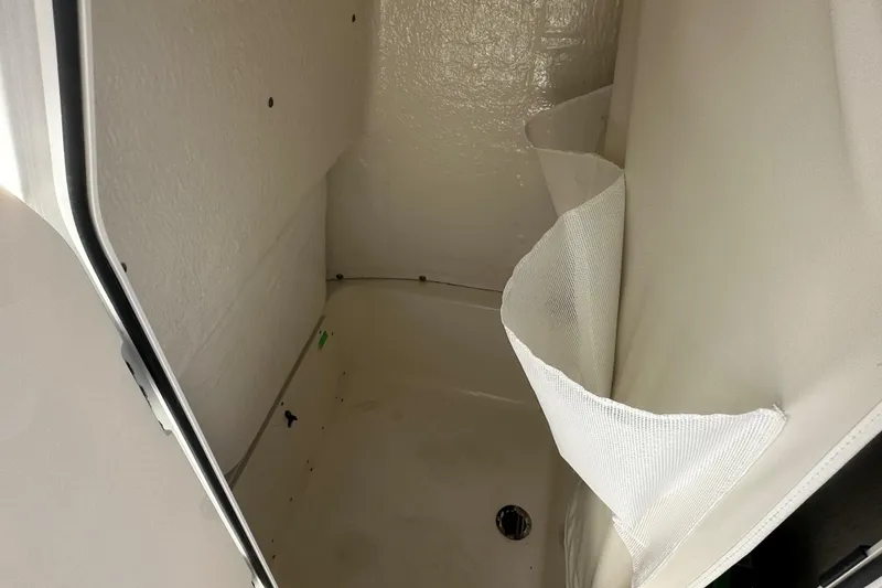 Slide: The Image of Interior view of a 2026 Key West 203 FS boat compartment with white walls and drain. - 4