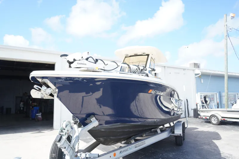 The Image of 2025 Scout 260 LXF boat on trailer, parked outside a building under a clear sky. - 0