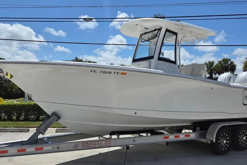 The Image of 2025 Sea Hunt Ultra 265 SE boat on trailer under clear blue sky. - 0
