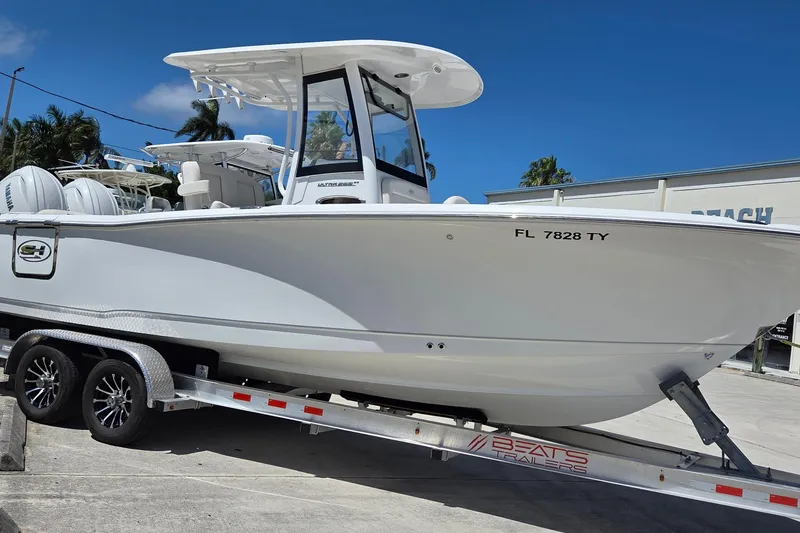 Slide: The Image of 2025 Sea Hunt Ultra 265 SE boat on trailer, parked outdoors under clear blue sky. - 1