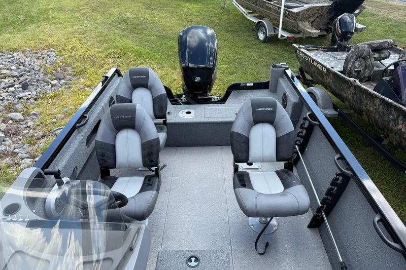 Slide: The Image of 2018 Crestliner 1650 Fish Hawk SC boat interior with seating and motor, parked on grass. - 4