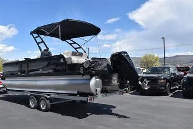 Slide: The Image of 2026 Princecraft Quorum 25 RL pontoon boat on trailer in parking lot. - 2
