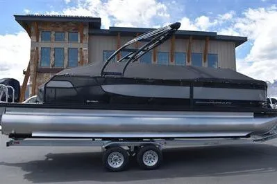 Slide: The Image of 2026 Princecraft Quorum 25 RL pontoon boat with black cover, parked on a trailer. - 31