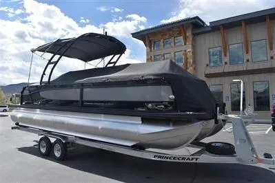 Slide: The Image of 2026 Princecraft Quorum 25 RL pontoon boat on trailer, parked outside a building. - 37