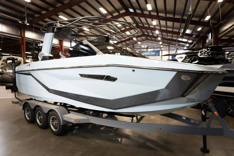 The Image of 2026 Nautique G23 boat in a warehouse on a trailer. - 1