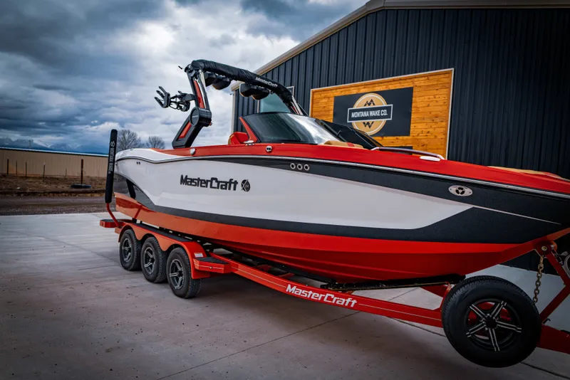 The Image of 2023 MasterCraft X24 boat on trailer in front of building. - 1