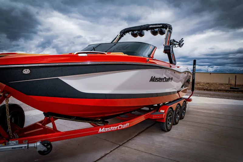 Slide: The Image of 2023 MasterCraft X24 boat on trailer under cloudy sky. - 4