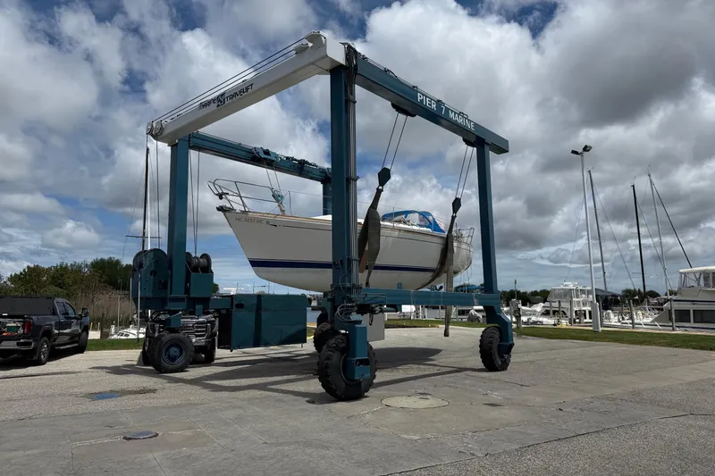 The Image of A 1986 CAL 33 sailboat lifted by a marine travel lift at a marina. - 1