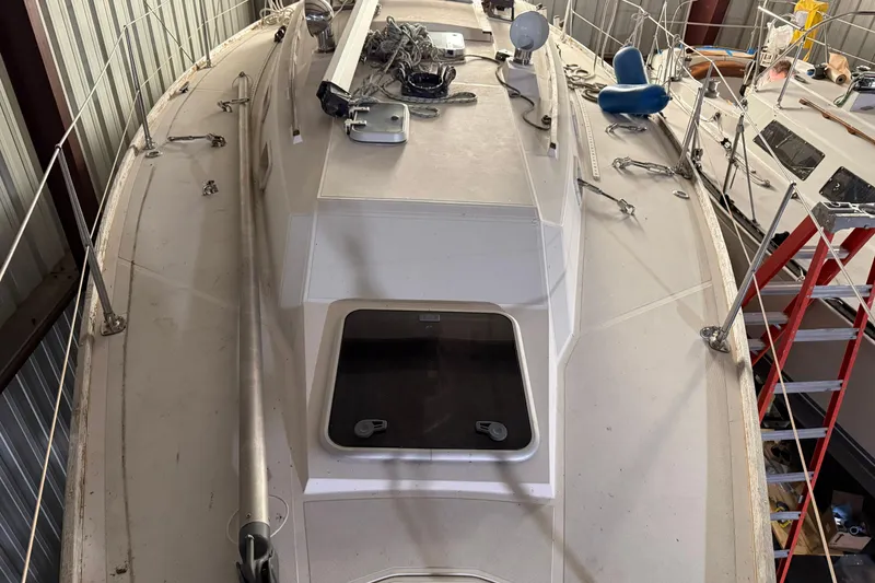 Slide: The Image of 1986 CAL 33 sailboat deck view in storage, featuring rigging and hatch. - 20