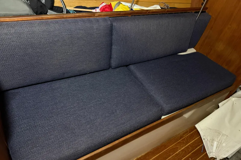 Slide: The Image of Navy blue cushioned seating inside a 1986 CAL 33 sailboat cabin. - 29