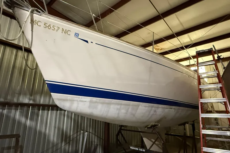 Slide: The Image of 1986 CAL 33 sailboat in storage, featuring a white hull with blue stripes. - 3