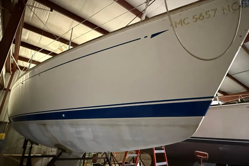 Slide: The Image of 1986 CAL 33 sailboat in storage, featuring a sleek white hull with blue accents. - 5