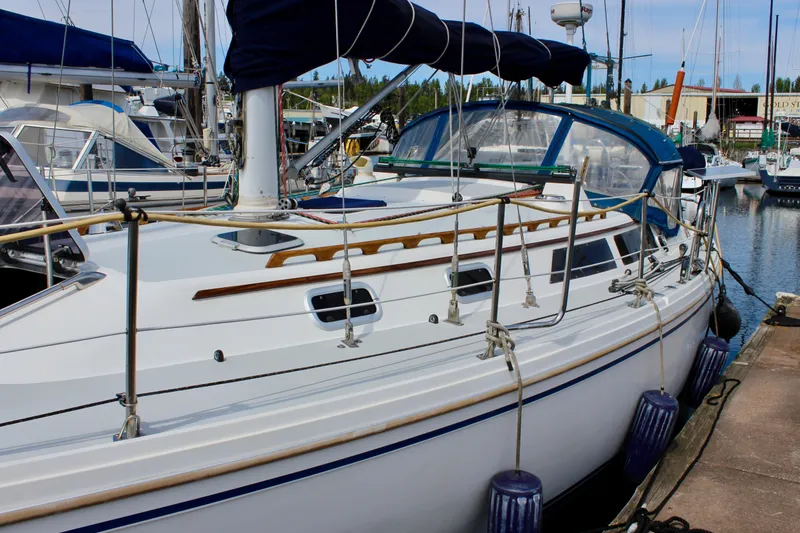 Slide: The Image of 1989 Catalina 36 sailboat docked at a marina, featuring a sleek white hull and blue accents. - 4
